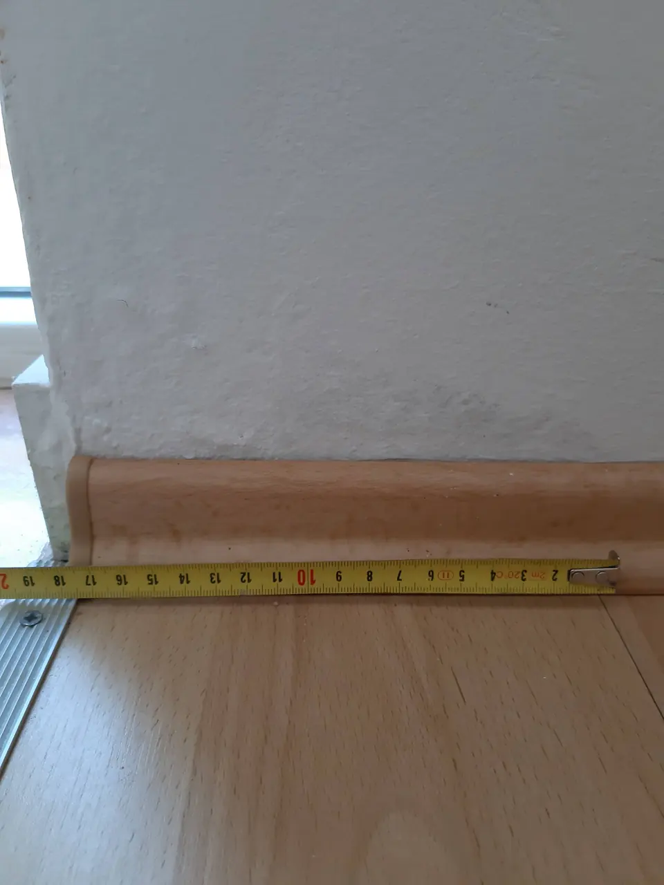 Laminat z zaključno letvijo ob steni, ob njej meter