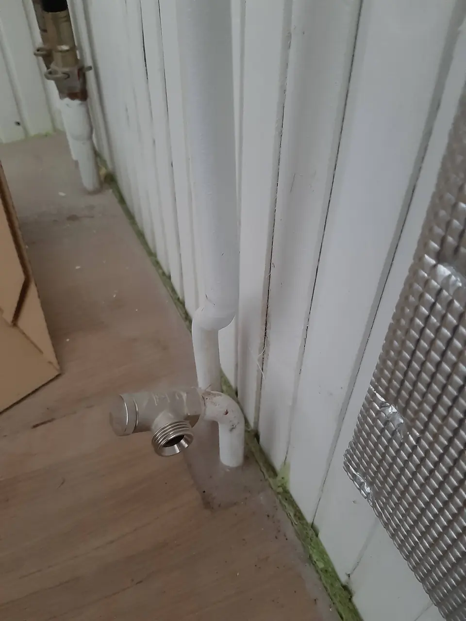 Priključki novega radiatorja in odbojna folija na steni za grelnim telesom